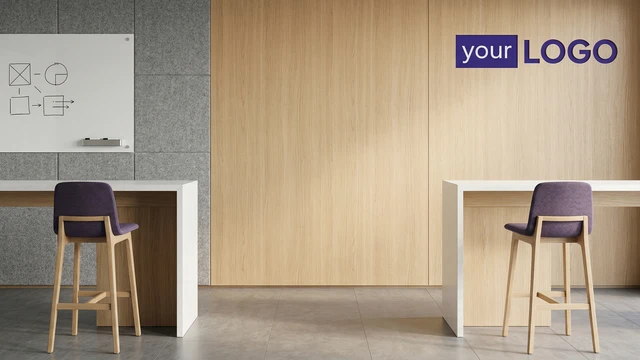Minimal modern office interior with wood panel wall, white desks, stools, and a mounted logo creating a clean professional backdrop.